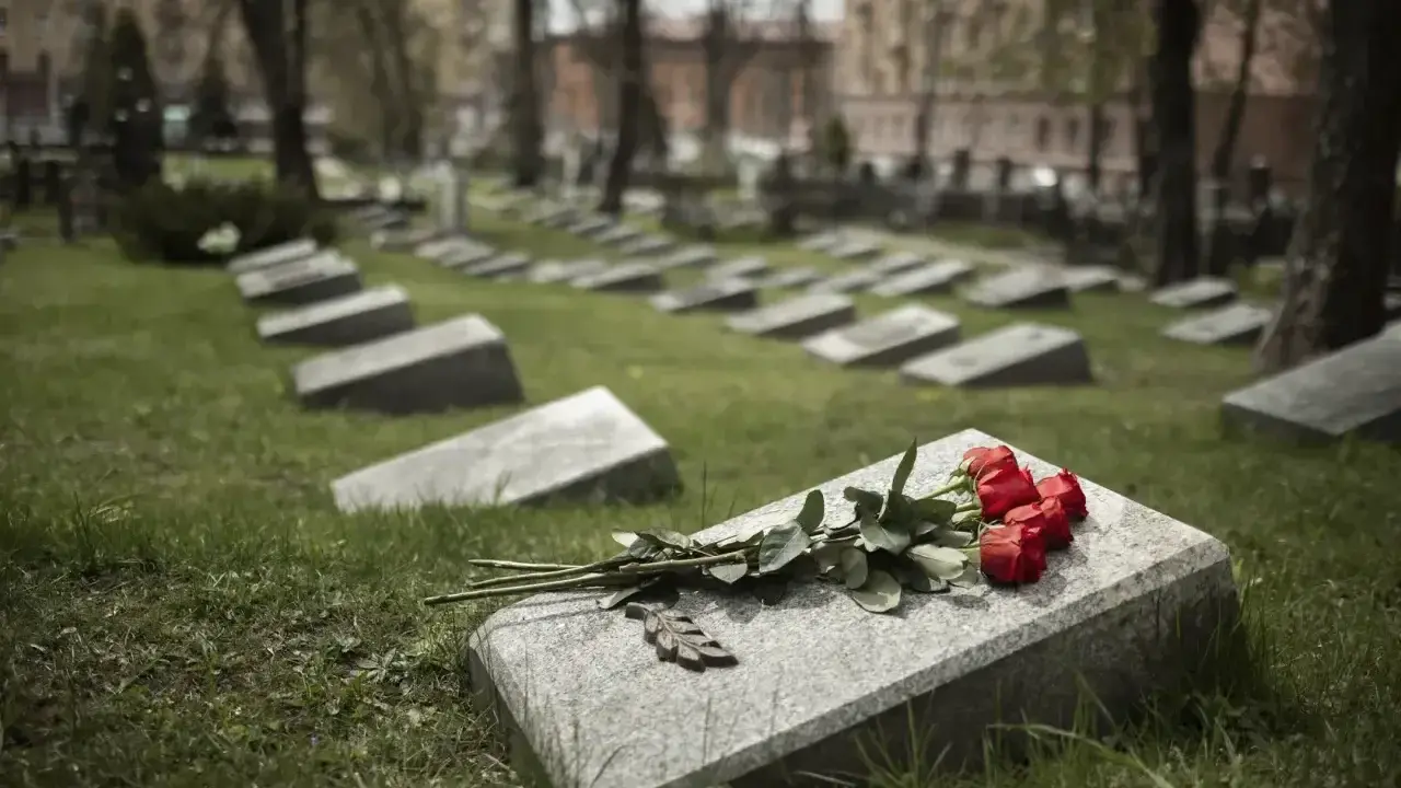 Czerwone róże na kamiennej płycie grobu to prosty sposób, jak udekorować grób bez pomnika.