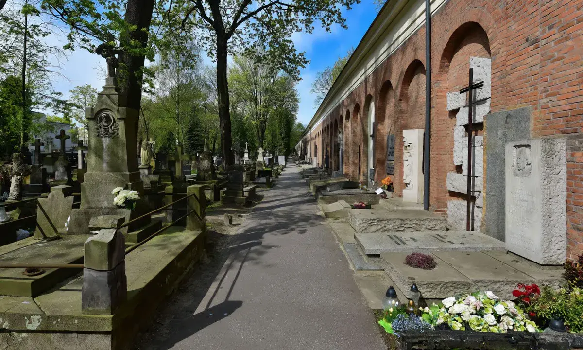 Aleja przez zabytkową nekropolię z nagrobkami i mauzoleami wzdłuż ceglanego muru z arkadami.