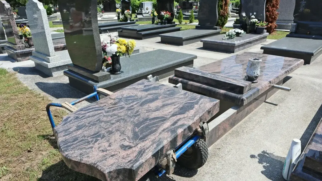 Na cmentarzu wózek transportuje płytę nagrobną. Kiedy można postawić pomnik po pogrzebie? Zwykle po kilku miesiącach, gdy ziemia osiądzie.