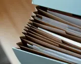 Segregator z dokumentami, symbol formalności po śmierci rodzica. Brązowe teczki i białe kartki.