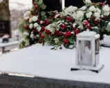 Wieniec dla taty: czerwone róże i białe kwiaty na śniegu, obok lampion.