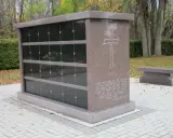 Kamienny grobowiec na urny z wygrawerowanym krzyżem i cytatem z Biblii. Obok ławka.