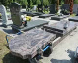Na cmentarzu wózek transportuje płytę nagrobną. Kiedy można postawić pomnik po pogrzebie? Zwykle po kilku miesiącach, gdy ziemia osiądzie.