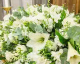 Piękna, biała wiązanka kwiatów z liliami, różami i zielonymi liśćmi.