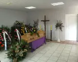 Drewniana trumna otoczona wieńcami i bukietami. Piękne kwiaty na trumnę tworzą smutną, ale uroczystą atmosferę.