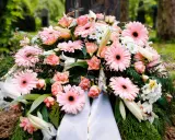Wieniec pogrzebowy z różowymi gerberami i różami. Szarfy z wieńców można wykorzystać do ozdoby grobu lub jako materiał do rękodzieła.