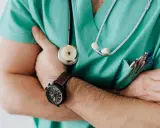 Lekarz w zielonym fartuchu ze stetoskopem i zegarkiem na ręku. Czy szpital informuje o zgonie w nocy?