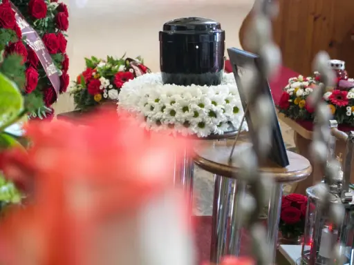 Urzna z prochami, otoczona kwiatami, obok wieńca z czerwonych róż. Czy kremacja boli? To pytanie, na które odpowiedź zna tylko zmarły.