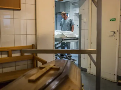 W prosektorium, po sekcji zwłok, pracownik pochyla się nad noszami. Czy po sekcji zwłok można otworzyć trumnę?