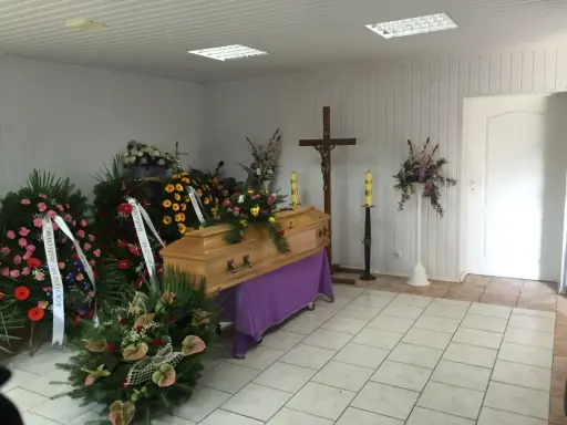 Drewniana trumna otoczona wieńcami i bukietami. Piękne kwiaty na trumnę tworzą smutną, ale uroczystą atmosferę.