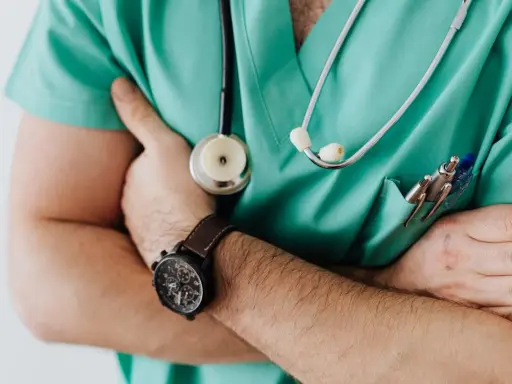 Lekarz w zielonym fartuchu ze stetoskopem i zegarkiem na ręku. Czy szpital informuje o zgonie w nocy?