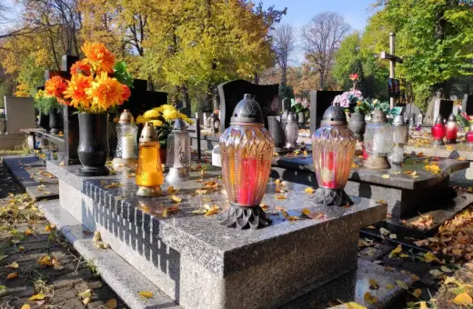 Jesienne zaduszki na cmentarzu. Zastanawiasz się, ile kosztuje miejsce na cmentarzu? Kwiaty i znicze na grobach.