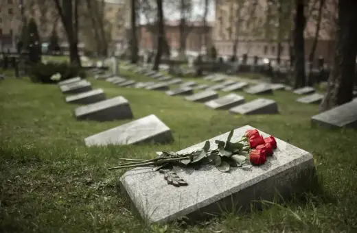 Czerwone róże na kamiennej płycie grobu to prosty sposób, jak udekorować grób bez pomnika.