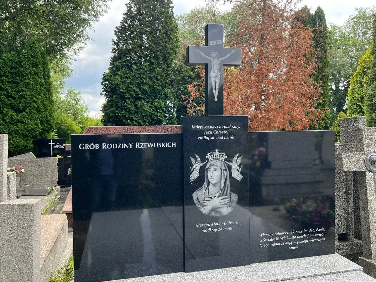 Elegancki, czarny granitowy grób rodziny Rzewuskich z krzyżem i wizerunkiem Matki Boskiej.