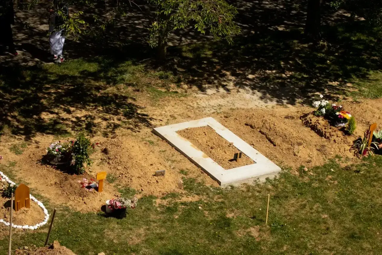 Świeży grób z wieńcem betonowym i kwiatami. Kiedy można postawić pomnik po pogrzebie? Gdy ziemia osiądzie.