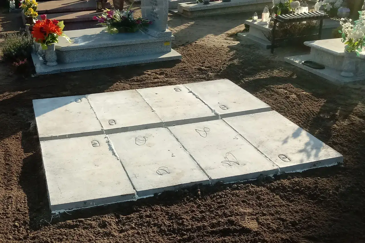 Nowy grób murowany czeka na pochówek. Betonowe płyty ułożone na ziemi, gotowe do zamknięcia.